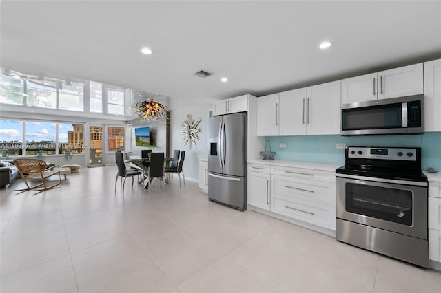 kitchen featuring appliances with stainless steel finishes, white cabinetry, and light tile floors