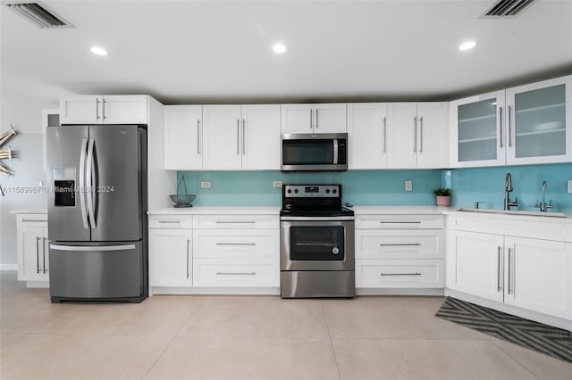 kitchen with white cabinets, appliances with stainless steel finishes, sink, and light tile flooring