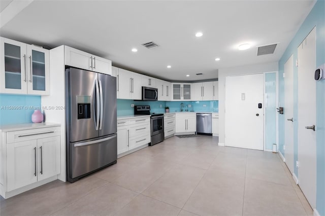 kitchen featuring appliances with stainless steel finishes, white cabinets, and light tile flooring