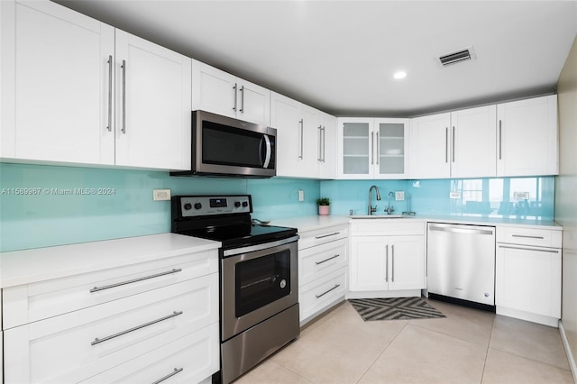 kitchen featuring tasteful backsplash, white cabinetry, appliances with stainless steel finishes, sink, and light tile floors