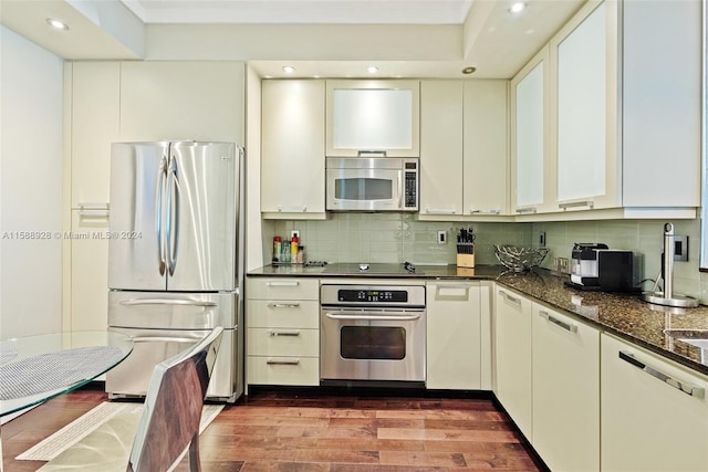 kitchen featuring dark hardwood / wood-style flooring, backsplash, white cabinetry, and appliances with stainless steel finishes