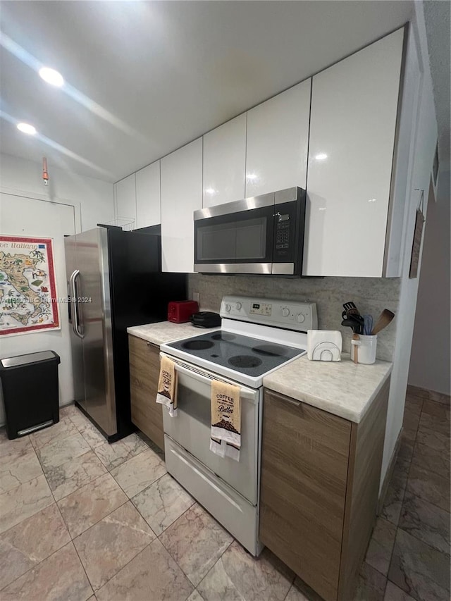 kitchen featuring appliances with stainless steel finishes, white cabinetry, and tasteful backsplash