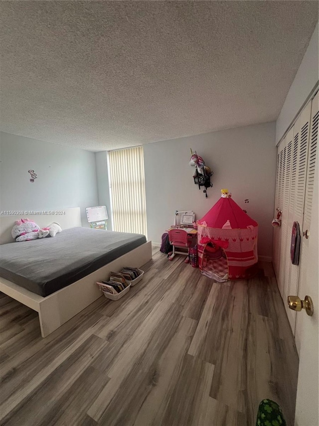 bedroom with a textured ceiling, wood-type flooring, and a closet