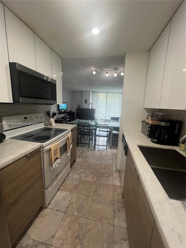 kitchen with white cabinetry, sink, and white range with electric cooktop