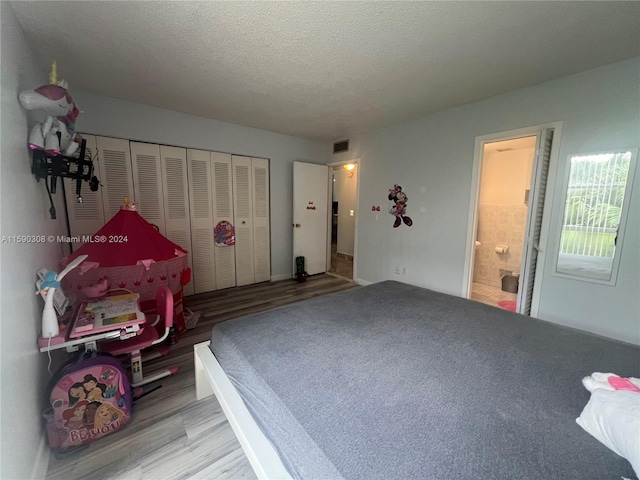 bedroom featuring connected bathroom, a textured ceiling, hardwood / wood-style flooring, and a closet