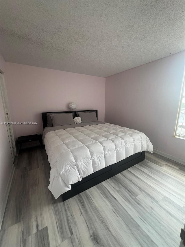 bedroom with a textured ceiling and light wood-type flooring