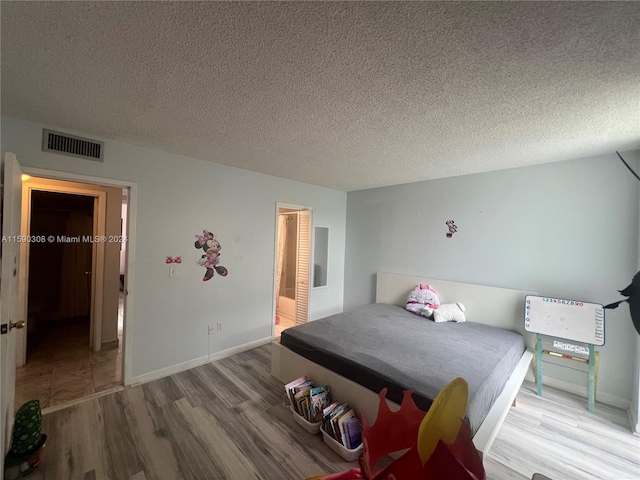 bedroom with a textured ceiling and hardwood / wood-style flooring