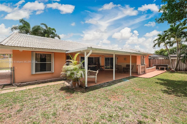 back of house with a patio area and a lawn