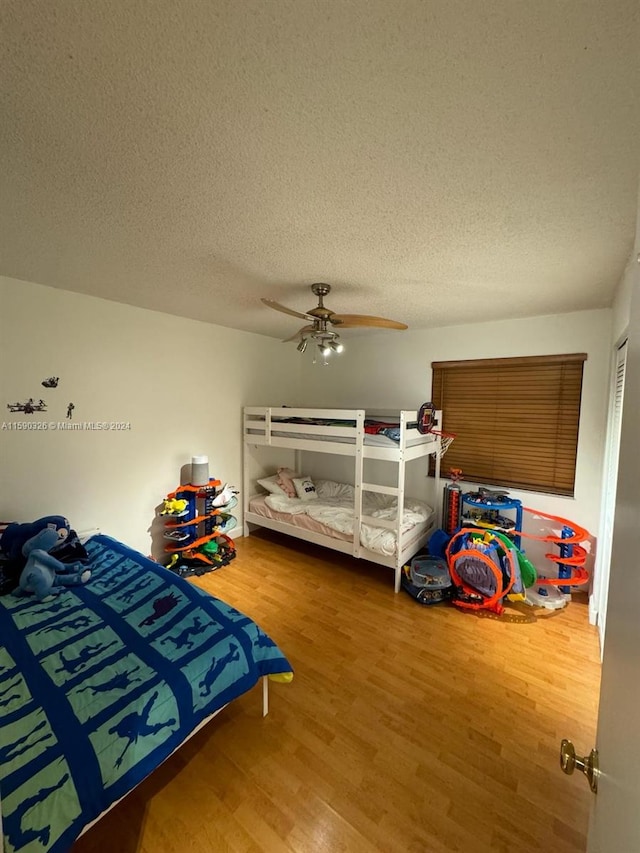 bedroom with ceiling fan, a textured ceiling, and hardwood / wood-style flooring