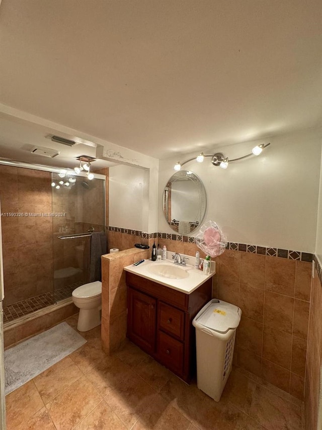 bathroom featuring walk in shower, tile floors, tile walls, vanity, and toilet