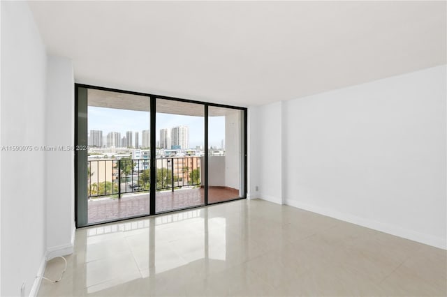 spare room with expansive windows and light tile patterned flooring