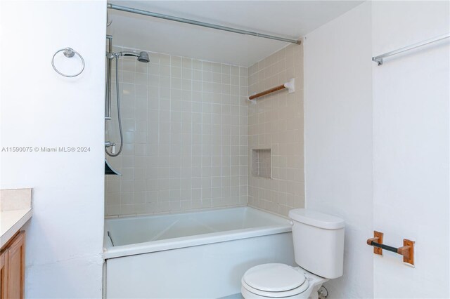 full bathroom featuring tiled shower / bath, vanity, and toilet