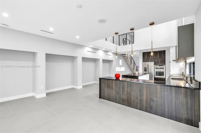 kitchen with appliances with stainless steel finishes, sink, pendant lighting, and dark brown cabinetry