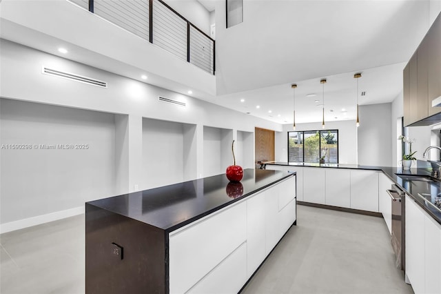 kitchen featuring sink, decorative light fixtures, stainless steel dishwasher, white cabinets, and a high ceiling