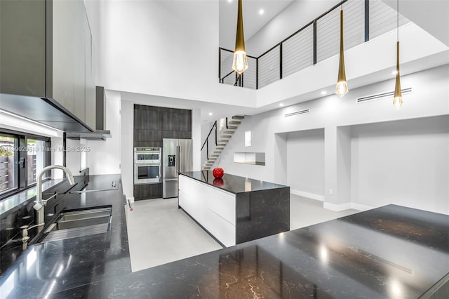 kitchen featuring appliances with stainless steel finishes, sink, hanging light fixtures, and a high ceiling