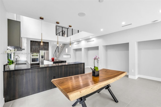 kitchen with appliances with stainless steel finishes, sink, hanging light fixtures, light tile patterned floors, and kitchen peninsula