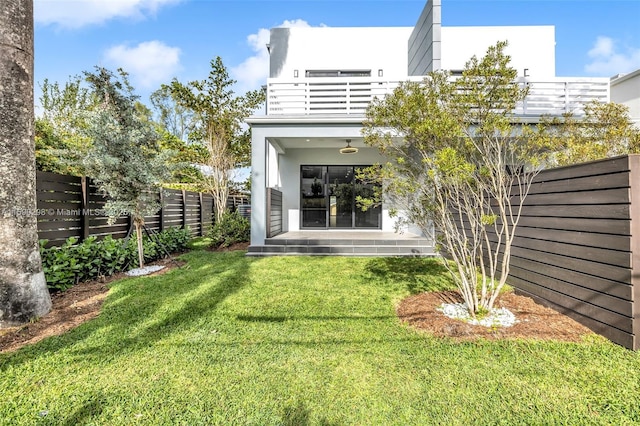 back of property featuring a balcony and a yard