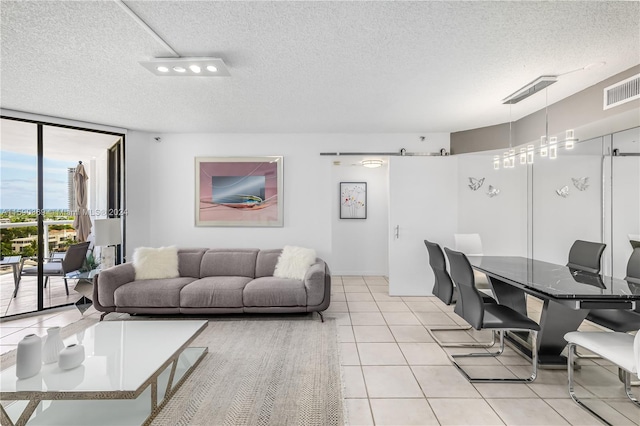 living room featuring a textured ceiling, a wall of windows, a barn door, and light tile patterned flooring