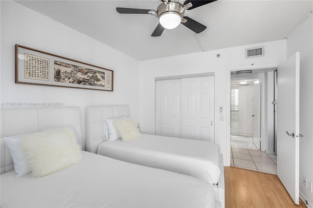 bedroom featuring a closet, ceiling fan, light hardwood / wood-style floors, and a textured ceiling