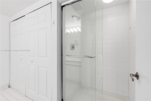 bathroom with a shower with door and tile patterned flooring