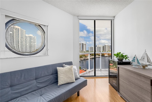 sitting room with wood-type flooring, a water view, a textured ceiling, and floor to ceiling windows