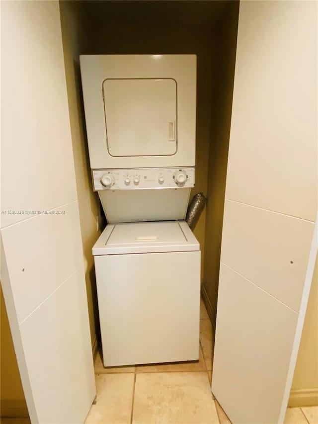 clothes washing area with stacked washing maching and dryer and light tile floors