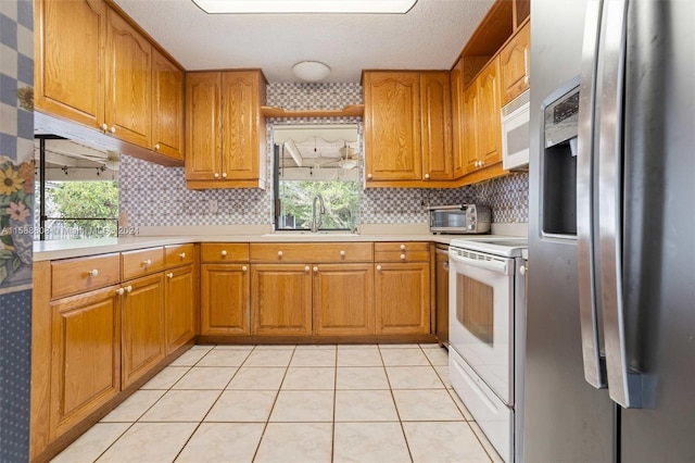 kitchen featuring sink, a healthy amount of sunlight, white appliances, and light tile floors