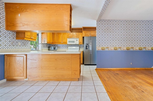 kitchen featuring white appliances, sink, light hardwood / wood-style floors, and backsplash