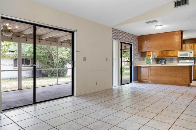 kitchen featuring sink, vaulted ceiling, tasteful backsplash, and light tile floors