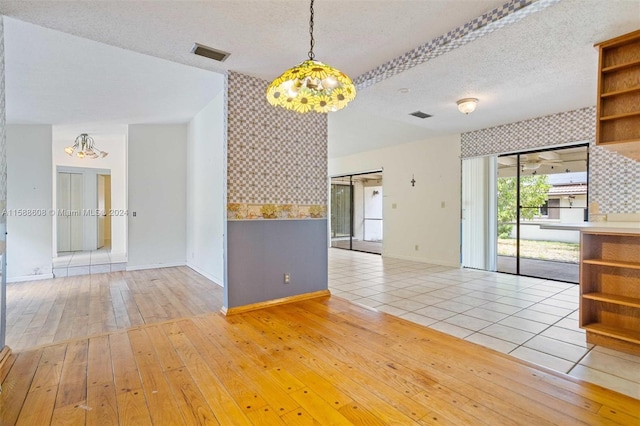 interior space with a barn door, a notable chandelier, a textured ceiling, and light tile floors