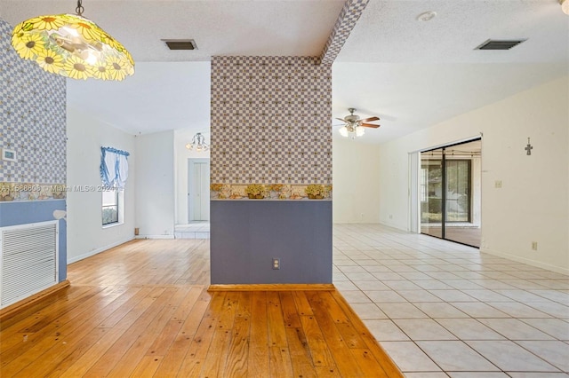 tiled empty room with a textured ceiling and ceiling fan