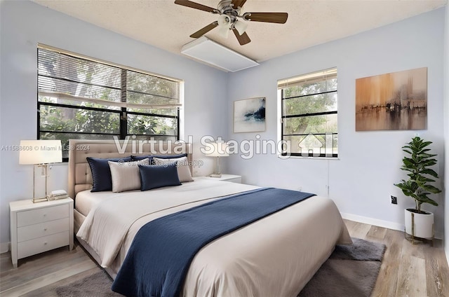 bedroom with a textured ceiling, ceiling fan, and light wood-type flooring