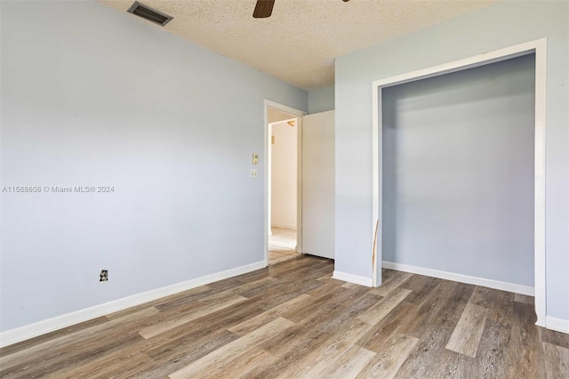 unfurnished bedroom featuring wood-type flooring, a closet, ceiling fan, and a textured ceiling