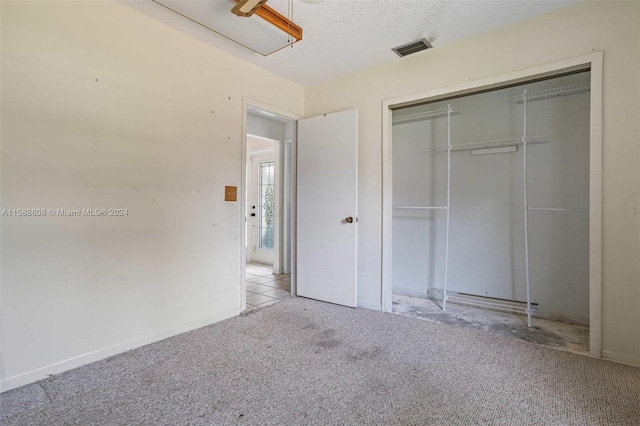 unfurnished bedroom with carpet, a closet, and a textured ceiling