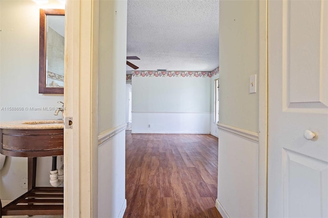 corridor with a textured ceiling and dark hardwood / wood-style flooring