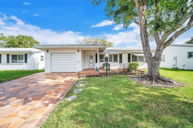 ranch-style home featuring a garage and a front lawn