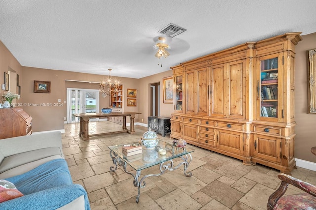 living room featuring a textured ceiling, ceiling fan with notable chandelier, and light tile patterned floors