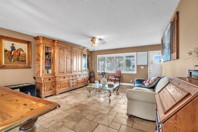 tiled living room featuring ceiling fan and a textured ceiling