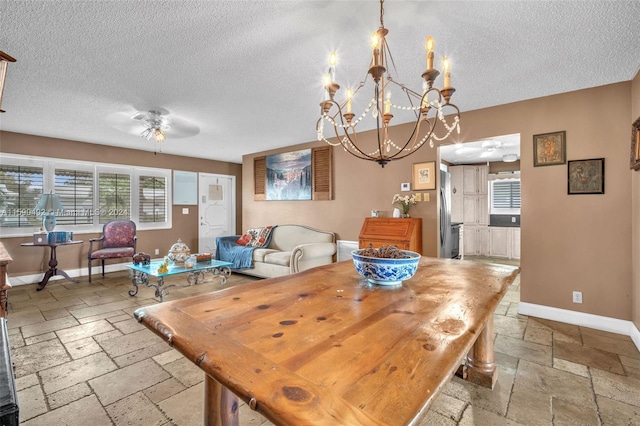 tiled dining room with ceiling fan with notable chandelier and a textured ceiling