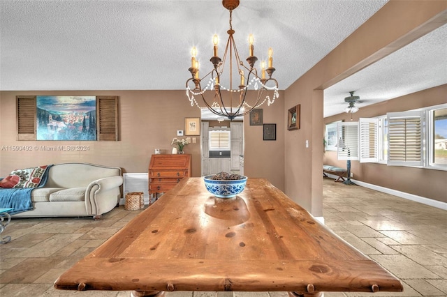 dining space with tile patterned flooring, ceiling fan with notable chandelier, and a textured ceiling