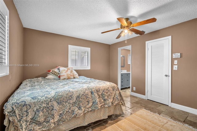 tiled bedroom featuring ensuite bath, a textured ceiling, and ceiling fan