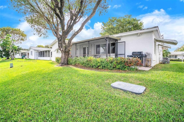 rear view of property with a sunroom and a yard