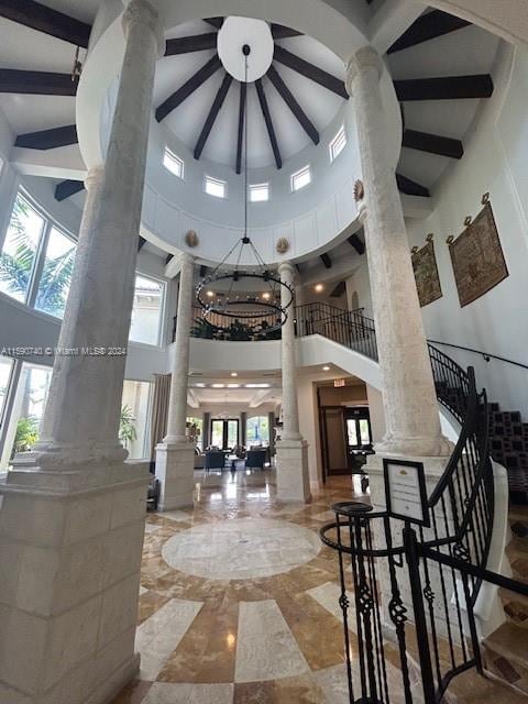 interior space featuring a towering ceiling, decorative columns, plenty of natural light, and tile floors