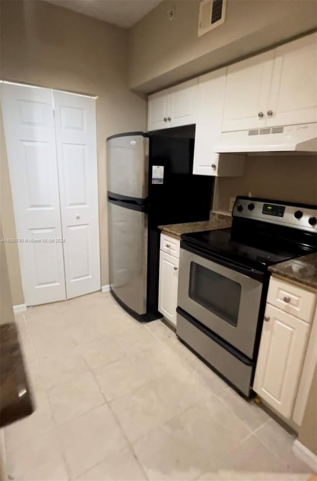 kitchen featuring white cabinets, light tile floors, appliances with stainless steel finishes, and premium range hood