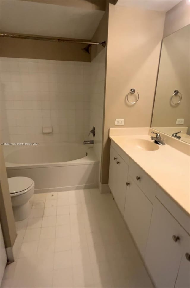 full bathroom with tiled shower / bath combo, toilet, tile floors, and large vanity