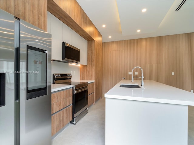 kitchen with a center island with sink, white cabinetry, sink, and stainless steel appliances