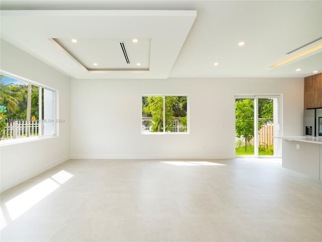 unfurnished living room with a tray ceiling and plenty of natural light