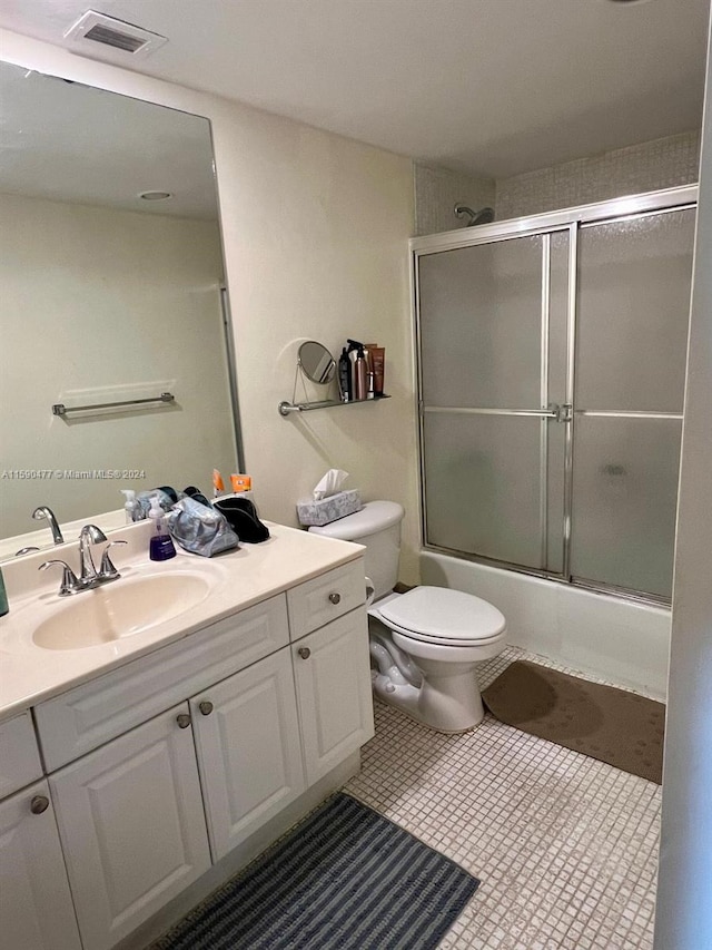 full bathroom featuring tile floors, bath / shower combo with glass door, toilet, and vanity