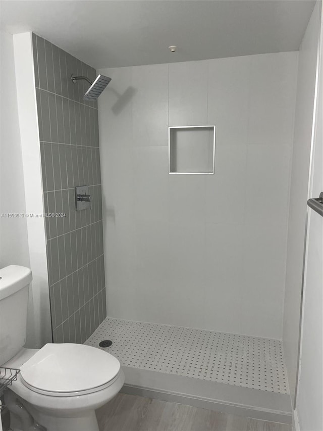 bathroom with tiled shower, hardwood / wood-style floors, and toilet