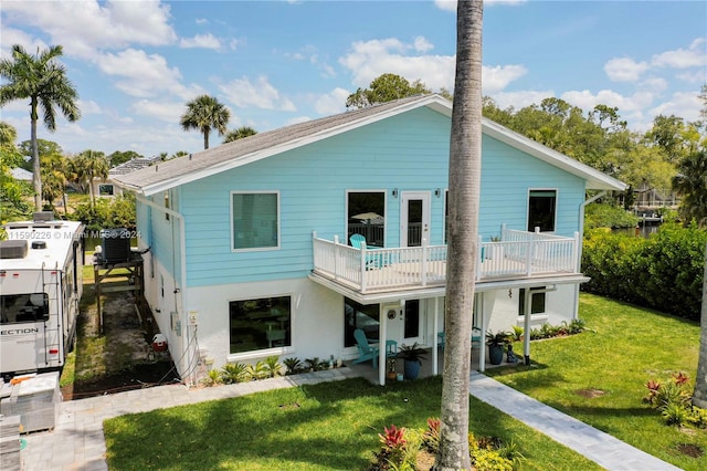 view of front of property with a front yard, a balcony, and central AC